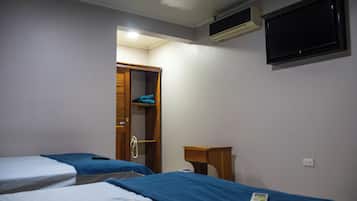 Un dormitorio con dos camas, un armario, una mesita de noche, un equipo de aire acondicionado y un televisor.