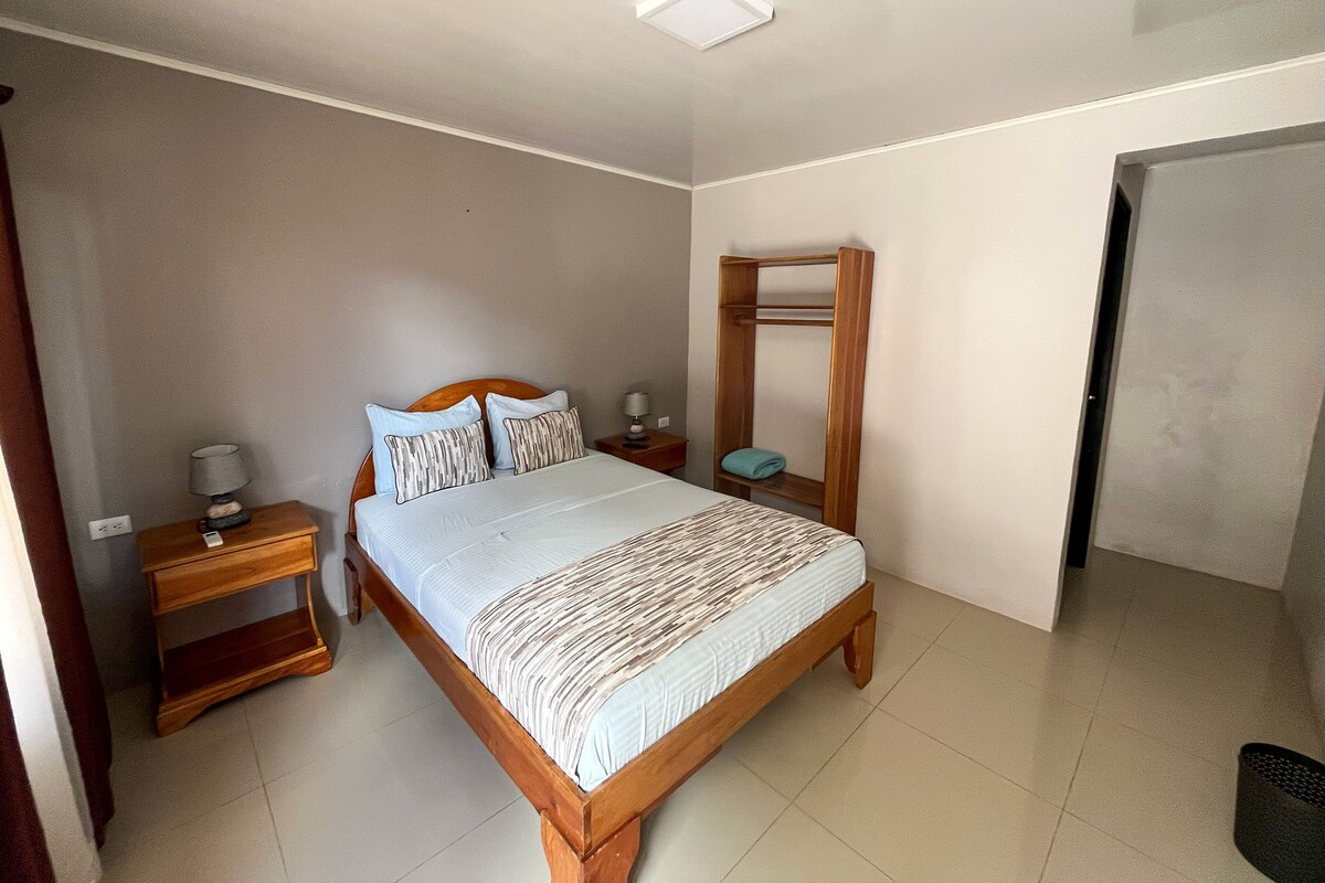 Un dormitorio con una cama de madera, una mesita de noche y un estante en la pared.