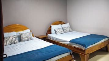 Two wooden beds with headboards, white bedding, and blue blankets.