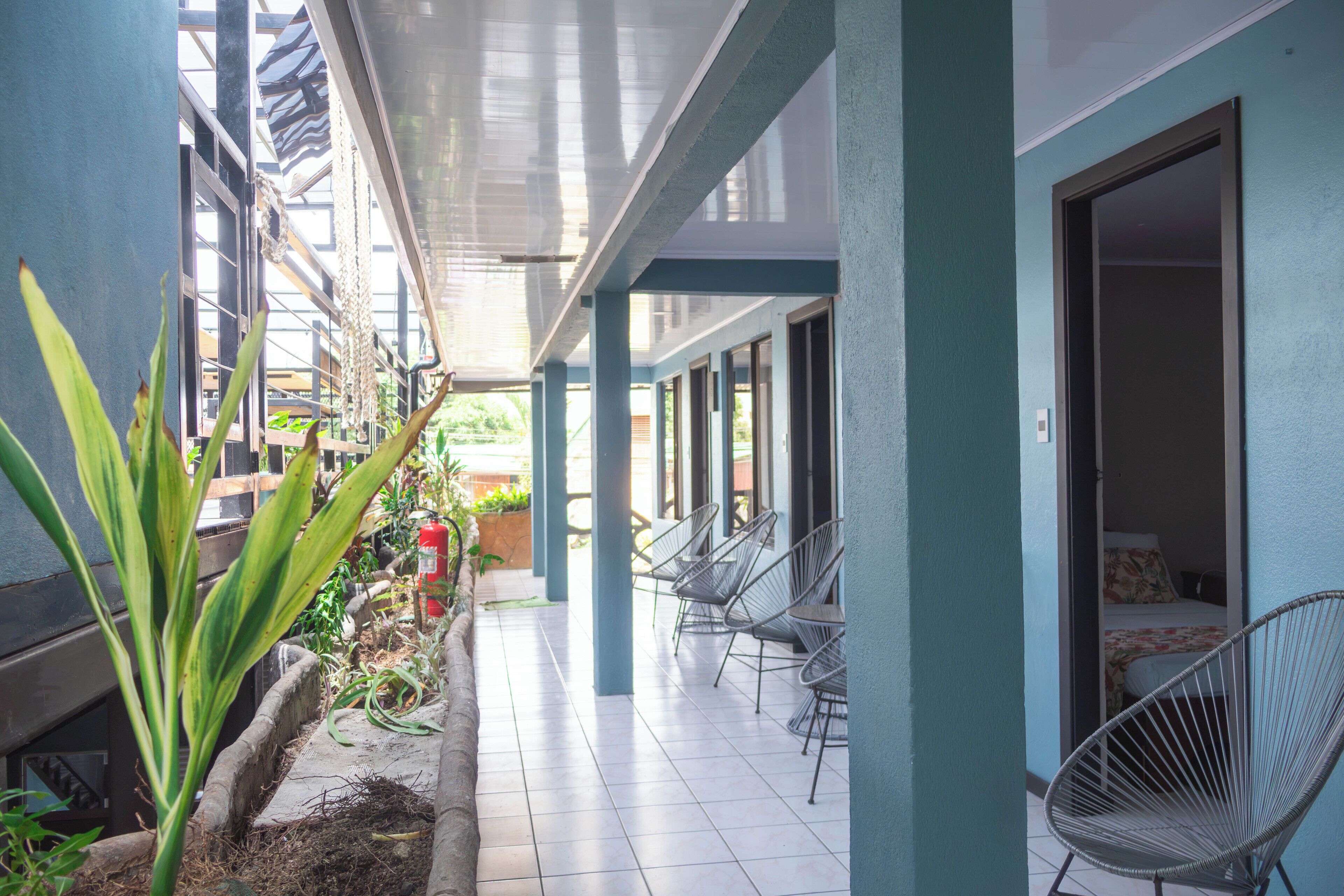 A covered outdoor area with chairs, a fire extinguisher, and plants.