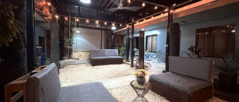 A cozy lounge area with a sofa, a small round table with a vase of flowers, and a ceiling fan.