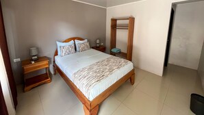 Un dormitorio con una cama de madera, una mesita de noche y un estante en la pared.