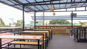 Un espacio al aire libre con mesas y sillas, un techo cubierto y vistas de los edificios circundantes.
