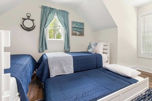A bedroom with two beds, a window with curtains, a painting, and a white headboard.