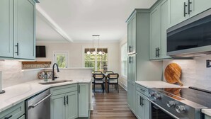 A modern kitchen with light green cabinets, a central island, and a built-in oven. - Cala Tortuga - Private dock, quiet cove, and games (Sparta)