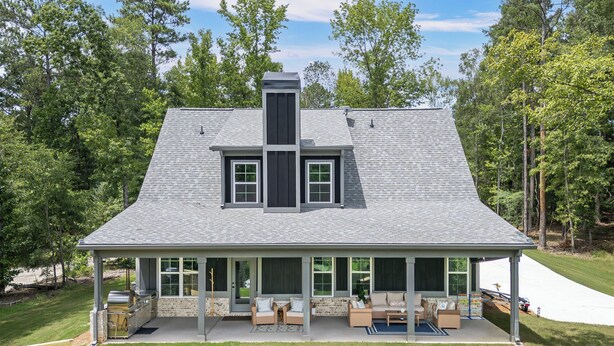 A two-story house with a covered patio area, a chimney, and a view of a wooded area. - Cala Tortuga - Private dock, quiet cove, and games (Sparta)