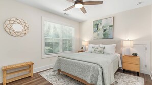 A bedroom with a bed, bedside tables, a ceiling fan, a window with blinds, a wall art piece, and a decorative mirror. - Cala Tortuga - Private dock, quiet cove, and games (Sparta)