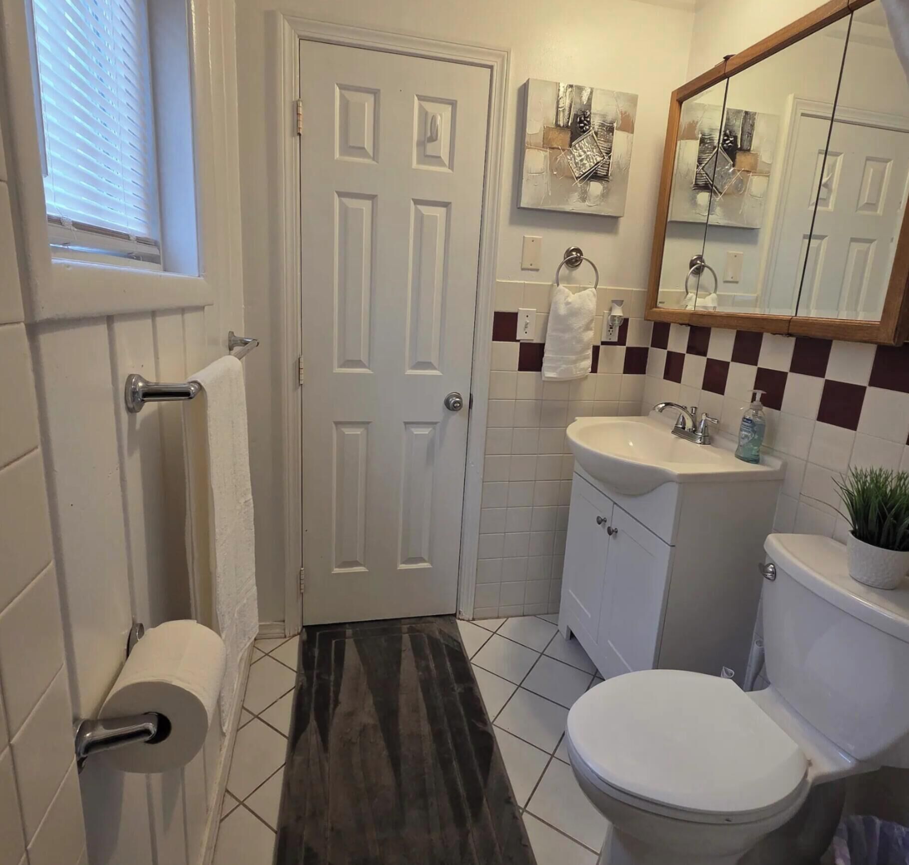 Une salle de bain équipée de toilettes, d’un lavabo, d’un miroir et d’un porte-serviettes.