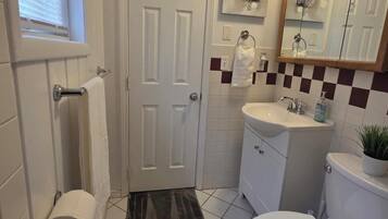 Une salle de bain équipée de toilettes, d’un lavabo, d’un miroir et d’un porte-serviettes.