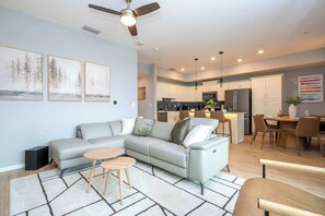A modern living room with a sectional sofa, a coffee table, and a ceiling fan. - Cozy 3BR Apartment Storey Lake Resort Near Disney (Kissimmee)