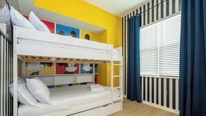Una cama litera con una cama inferior, una ventana con persianas y una pared decorada con ilustraciones coloridas.