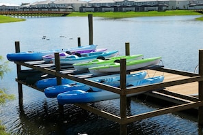 A dock with several kayaks and a row of houses in the background. - Cozy 3BR Apartment Storey Lake Resort Near Disney (Kissimmee)
