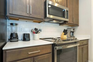 A modern kitchen with stainless steel appliances, a white countertop, and wooden cabinets. - 6BR Villa Pool & Lake View Balmoral Resort (Haines City)