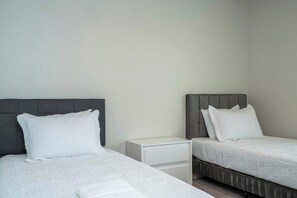 A hotel room with two single beds, a nightstand, and a white dresser. - 6BR Villa Pool & Lake View Balmoral Resort (Haines City)