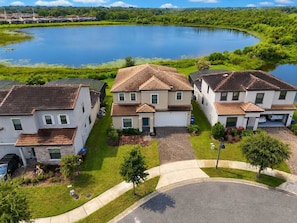 A residential area with houses, a lake, and a paved driveway. - 6BR Villa Pool & Lake View Balmoral Resort (Haines City)