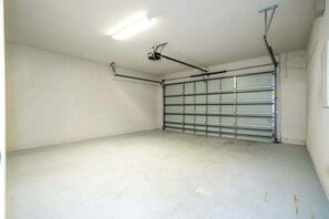 A clean, empty garage with a metal garage door, fluorescent lighting, and a ceiling-mounted projector. - 6BR Villa Pool & Lake View Balmoral Resort (Haines City)