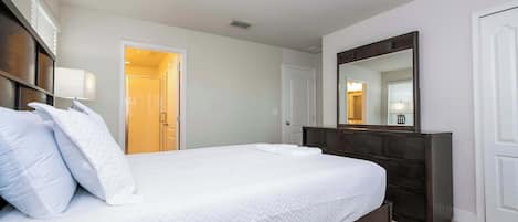 Una habitación de hotel con una cama grande, un aparador, un espejo y una puerta que da a un baño.