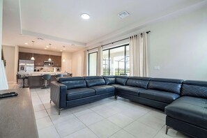 Una sala de estar moderna con un sofá modular, una zona de cocina y un comedor.