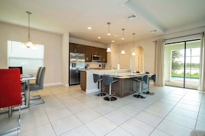 A modern kitchen with a central island, stainless steel appliances, and a dining area with bar stools.