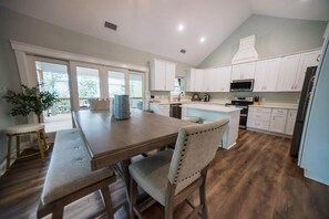 A spacious kitchen with a central island, white cabinetry, and a large window providing natural light. - Island Oasis with Included Golf Cart (Dauphin Island)