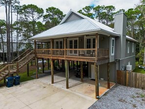 A two-story house with a covered porch and a garage. - Island Oasis with Included Golf Cart (Dauphin Island)