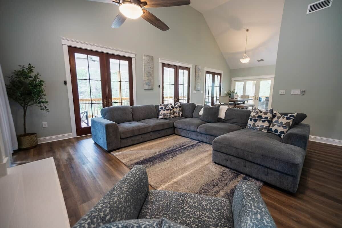 A spacious living room with a large sectional sofa, a ceiling fan, and a view to the outside.