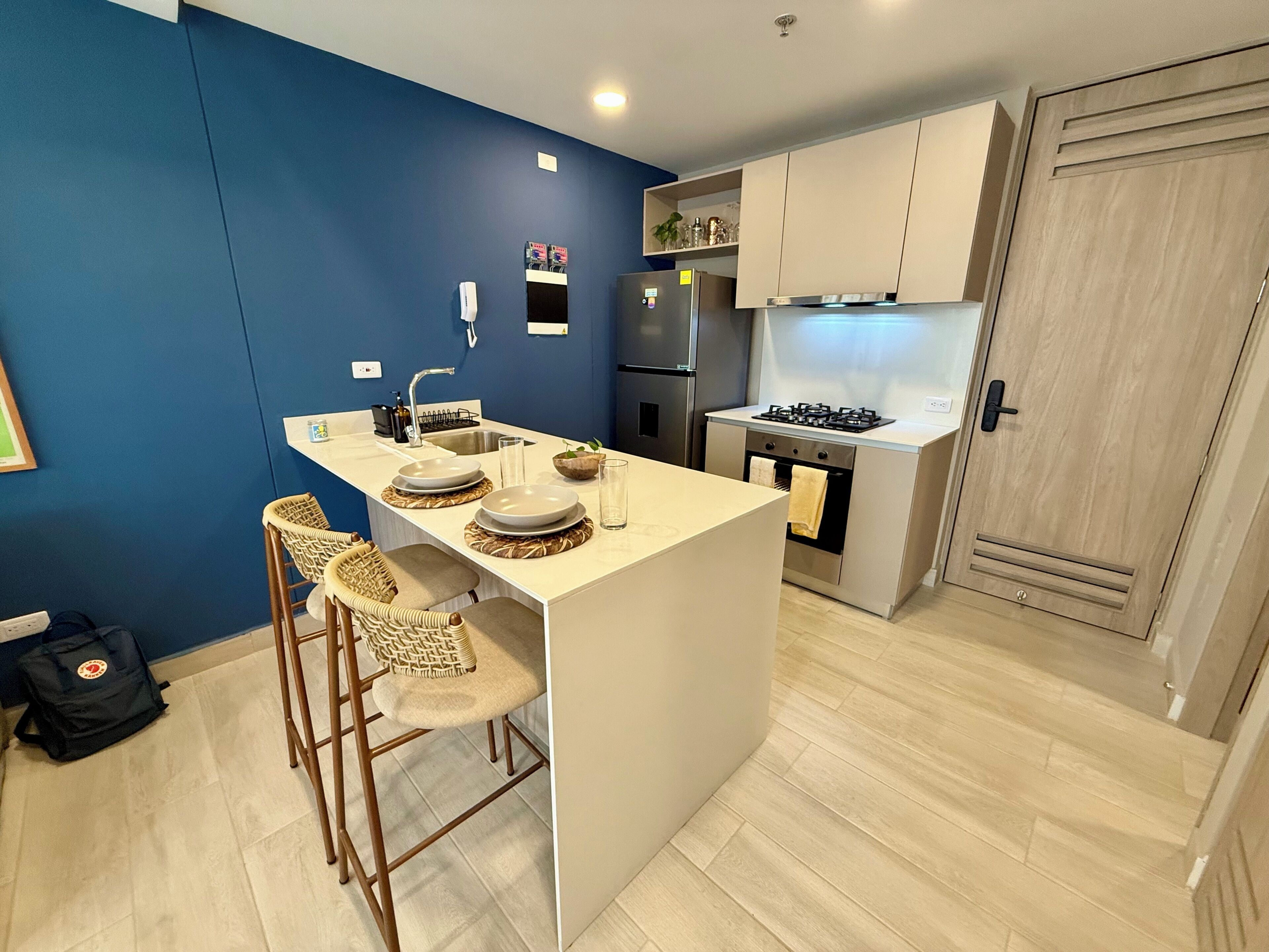 A compact kitchen with a central island, bar stools, a refrigerator, and a stove.