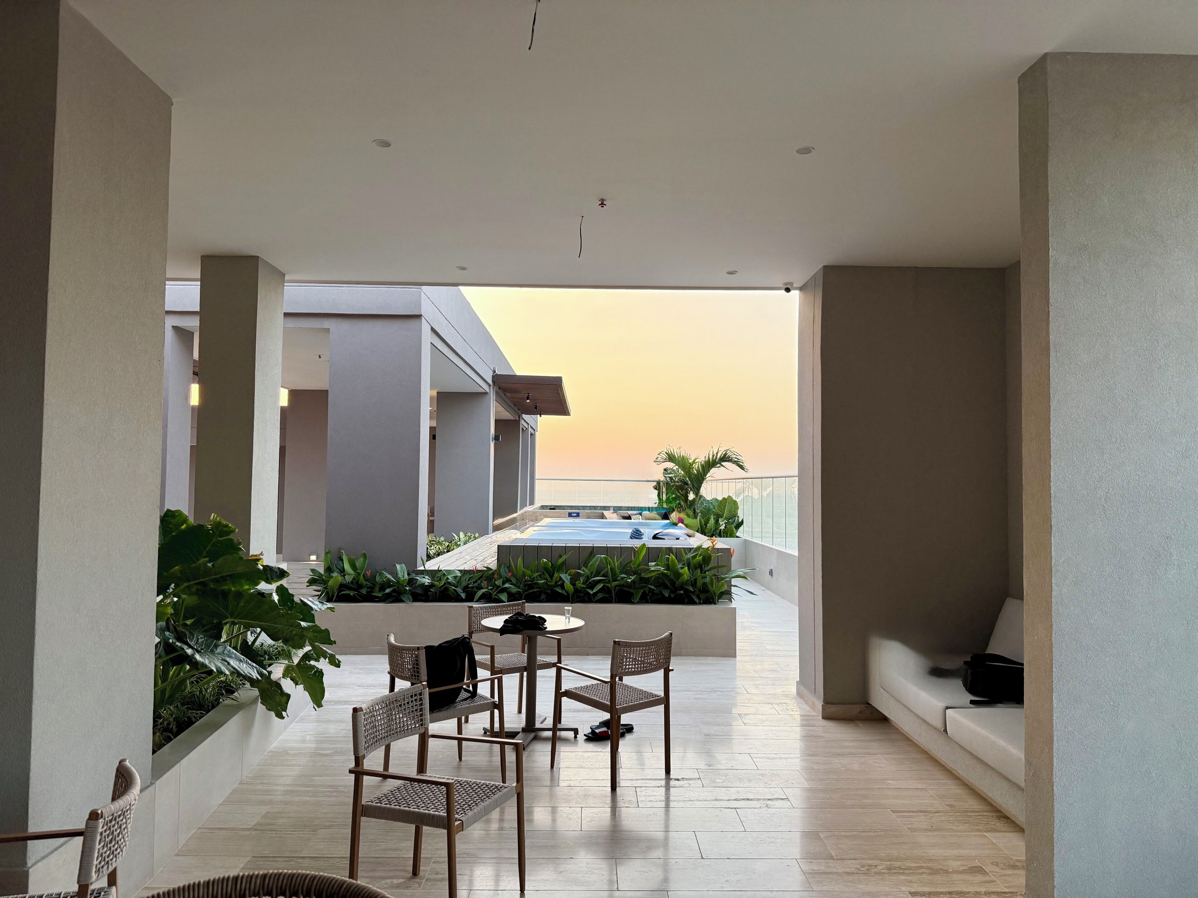 A modern outdoor patio with a pool, seating area, and plants.