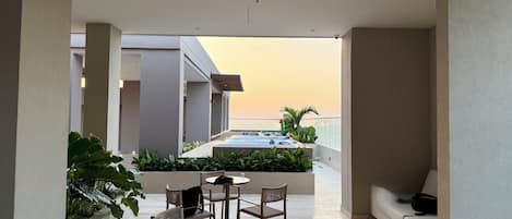 A modern outdoor patio with a pool, seating area, and plants.