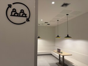 Ein modernes Interieur mit einem runden Schild, das zwei Personen und einen Pfeil zeigt, einer Bank und Pendelleuchten.