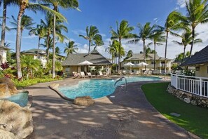 A resort pool area with lounge chairs, palm trees, and a clear sky. - Ocean-View KoOlina walk to Beach, Lagoons & Dining (Kapolei)