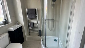 Ein modernes Badezimmer mit einer gläsernen Dusche, einer Toilette und einem Handtuchhalter.