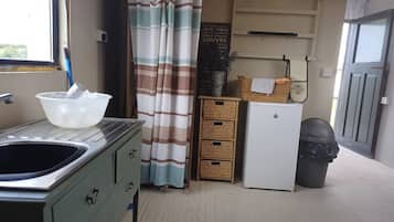 A compact kitchenette with a sink, a small refrigerator, and a cabinet.