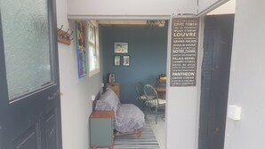 A narrow hallway with a striped rug, a bed with floral bedding, a wooden cabinet, and a chair. - Tiny living on the Wild Atlantic Way (Tralee)