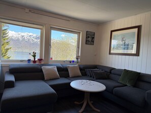 Una sala de estar moderna con un sofá modular, una mesa de centro redonda y amplias ventanas que ofrecen vistas a un paisaje nevado.