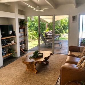 Ein Wohnzimmer mit Fernseher, Bücherregalen, Couchtisch und Sofa.