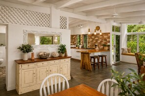 A spacious kitchen with a central island, white cabinetry, and a large window overlooking greenery. - Cairns Beachfront Retreat (East Trinity)