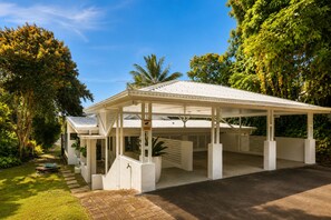 A covered outdoor area with a white roof, surrounded by lush greenery and trees. - Cairns Beachfront Retreat (East Trinity)