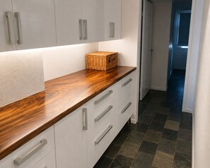 A kitchen with white cabinets, a wooden countertop, and a basket. - Cairns Beachfront Retreat (East Trinity)