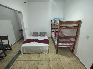 A small, single-room accommodation with a bed, a bunk bed, a chair, and a small table.
