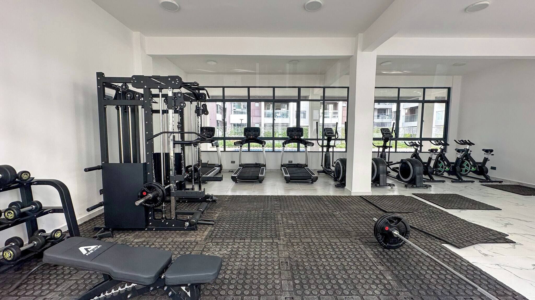 Un gimnasio con equipamiento de ejercicio, cintas de correr y máquinas de pesas.