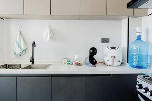 A kitchen with a sink, a coffee machine, a kettle, and a water dispenser. - Nairobi Jkia Retreat With Pool Wifi and 24hrs Gym (Syokimau)