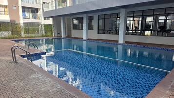 Una piscina rectangular con un diseño de mosaicos azules, rodeada por un sendero de ladrillo.