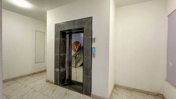 Un pasillo con una puerta espejada que da a una escalera.
