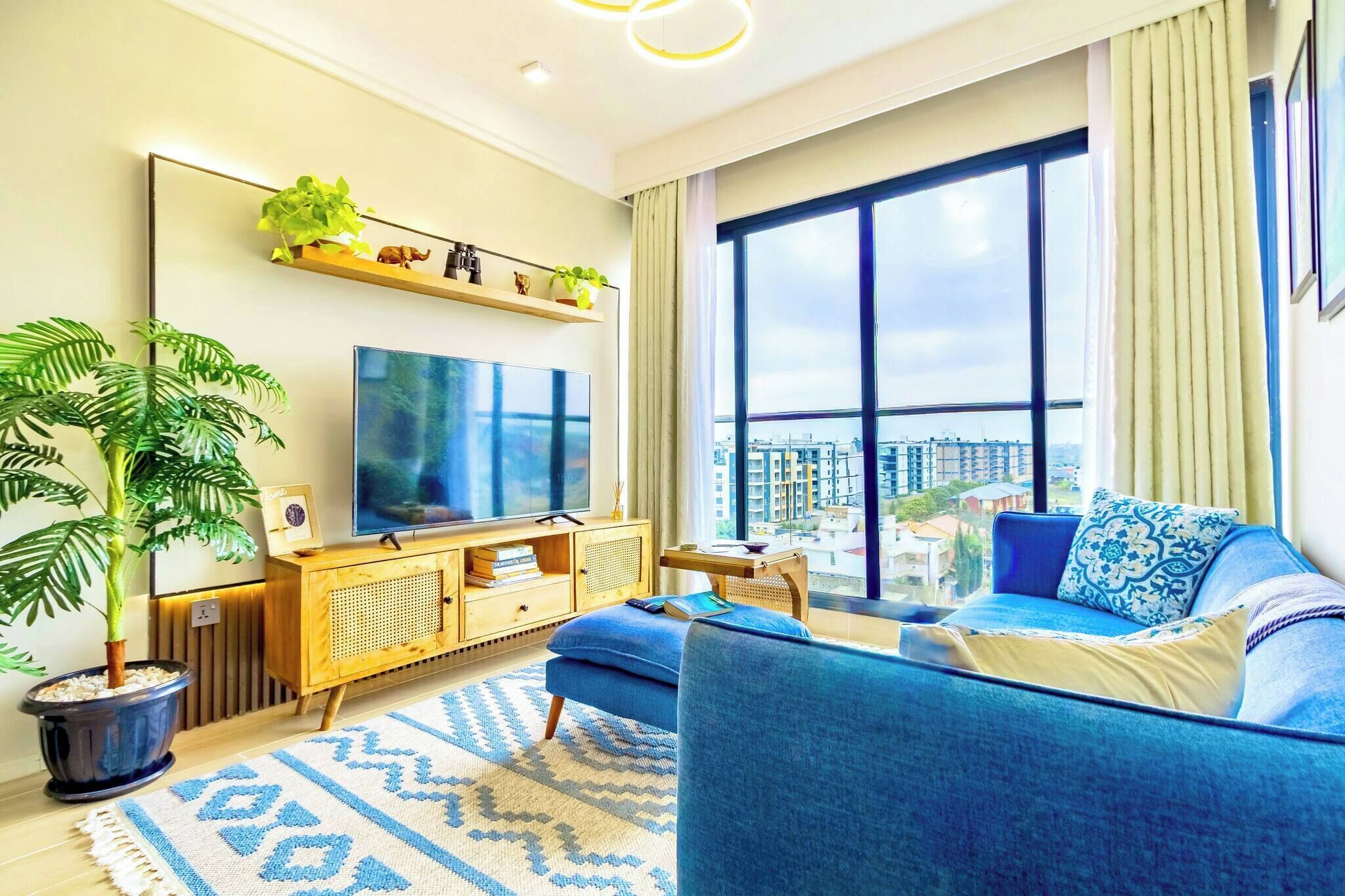 A modern living room with a large TV, a sofa, a coffee table, and a potted plant.