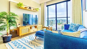 Un salon moderne avec un grand téléviseur, un canapé, une table basse et une plante en pot.