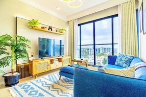 A modern living room with a large TV, a sofa, a coffee table, and a potted plant. - Nairobi Jkia Retreat With Pool Wifi and 24hrs Gym (Syokimau)