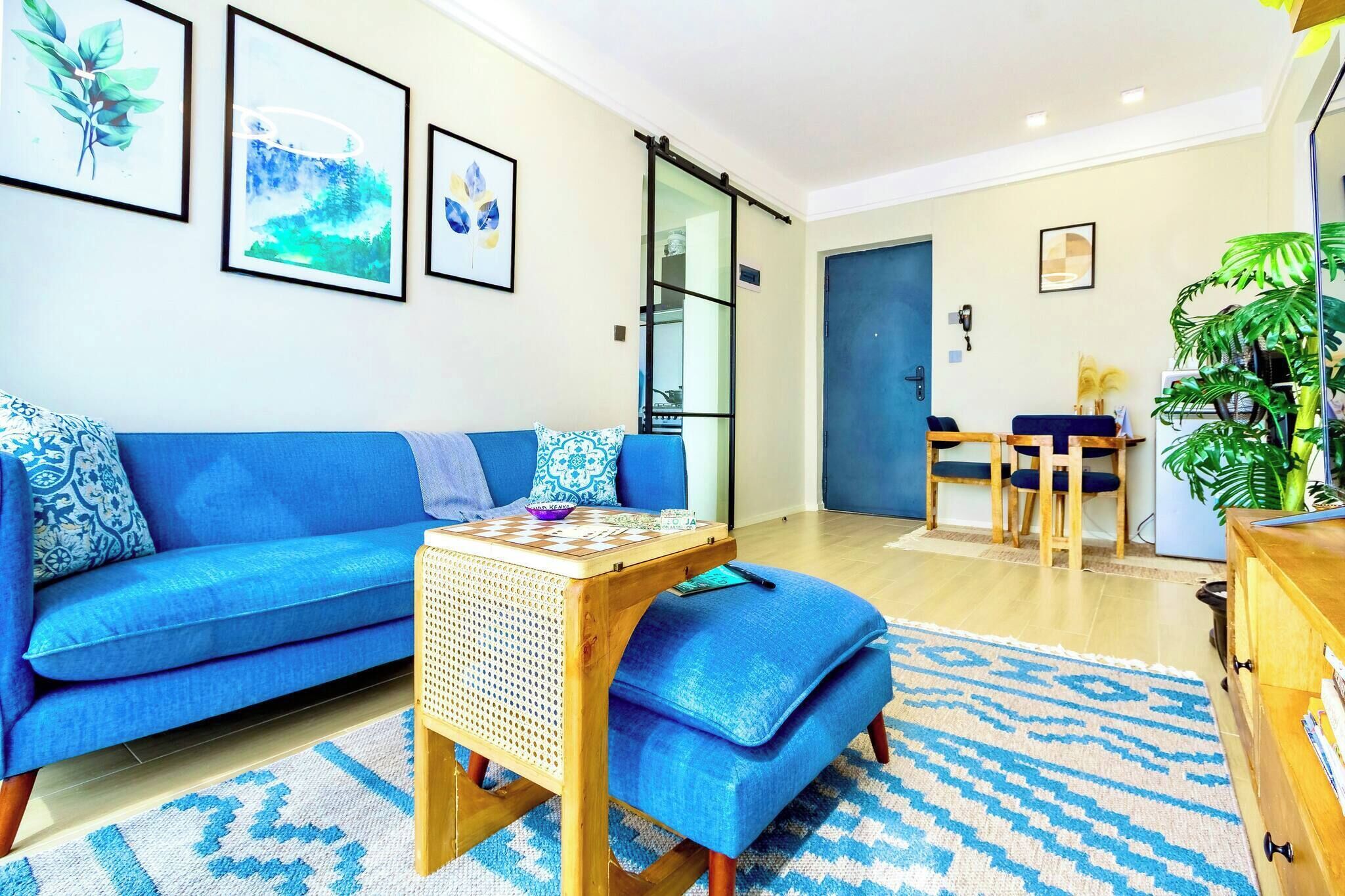Una sala de estar con un sofá azul, una mesita de madera y un tapete azul estampado.