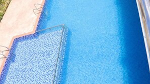 Une piscine rectangulaire à l’eau d’un bleu limpide, entourée d’une terrasse en béton.