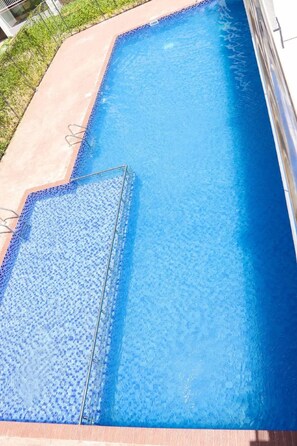 A rectangular swimming pool with a clear blue water surface, surrounded by a concrete deck. - Nairobi Jkia Retreat With Pool Wifi and 24hrs Gym (Syokimau)